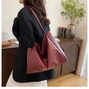 Burgundy faux leather tote bag shown in a lifestyle setting worn on the shoulder
