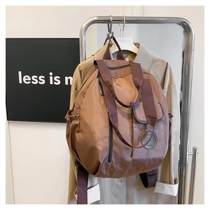 Detail of brown nylon backpack showing waterproof texture and round rubber logo patch