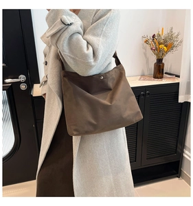 Close-up of brown canvas tote bag featuring magnetic metal clasp and wide shoulder strap