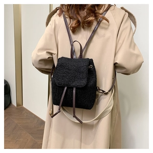 Detailed view of black wool fabric mini backpack with brown leather straps on model