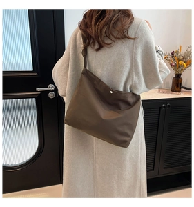 Detail view of coffee-colored frosted tote bag with metal snap and wide shoulder strap