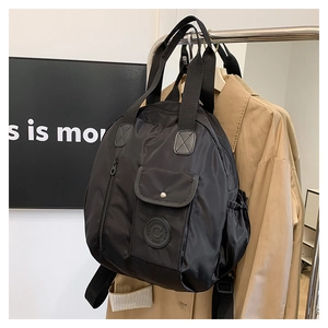 Detail view of black nylon backpack with flap pocket and side elastic storage pocket