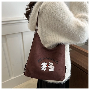 Brown suede bucket bag detail showing cute puppy embroidery and adjustable shoulder strap