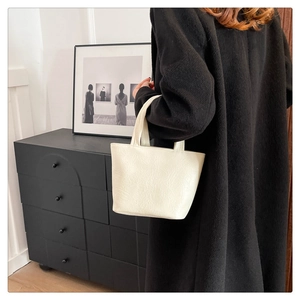 Detail of minimalist cream tote bag showing soft pleated texture and stylish shoulder strap