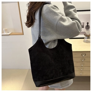Detail of black corduroy tote bag showing large capacity and leather strap on a model