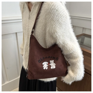 Close-up of brown suede tote bag featuring detailed cartoon bear embroidery and lettering