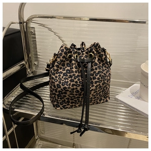 Detail of leopard print drawstring bucket bag with gold hardware and leather straps