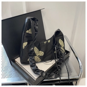 Detail of black butterfly embroidery bag with textured fabric and scrunchie strap