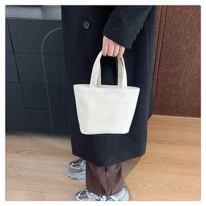 Detailed texture of white soft leather tote bag held by a model in a winter outfit