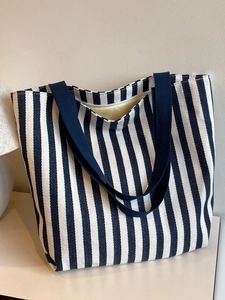 Detail of navy blue striped canvas tote bag showing top zipper and yellow interior lining