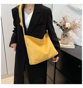 Detail of yellow canvas tote bag featuring adjustable knotted strap and magnetic closure