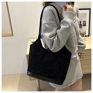 Detail of black corduroy tote bag with leather base shown in a lifestyle studio setting