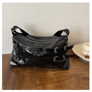 Close-up of glossy black leather handbag featuring stylish buckle straps and silver hardware