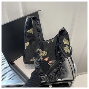 Detail of butterfly embroidery on black shoulder bag with stylish scrunchie handle design