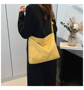Macro detail of yellow matte tote bag with metallic buckle worn by a model in black blazer