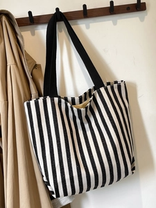 Detailed view of the large capacity striped canvas tote bag hanging on a wooden hook