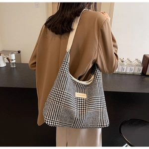 Classic black and white houndstooth tote bag with fashion label and cream strap on model