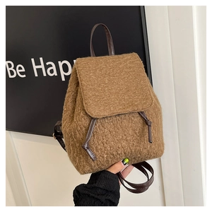 Detail of soft brown plush material texture and brown faux leather drawstring on backpack