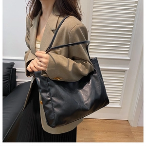 Detailed view of large black tote bag featuring premium leather texture and dual shoulder straps