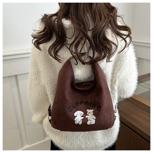 Detailed embroidery of two bears on dark coffee brown suede hobo bag shown on a model back