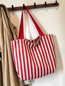 Close-up of red and white striped canvas tote bag hanging on a wooden hook