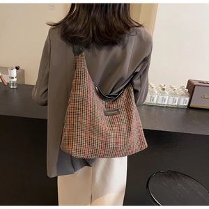 Detail of checkered houndstooth tote bag with leather straps on model in cafe