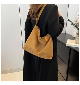 Detail of knot shoulder strap and magnetic closure on mustard suede tote bag