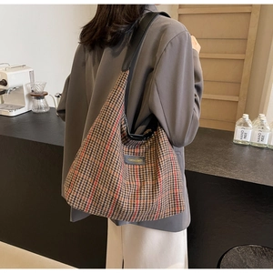 Detail of vintage plaid tote bag with leather straps and classic fashion label brand