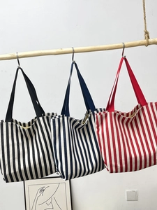 Detailed view showing three striped canvas tote bags in black, blue, and red colors