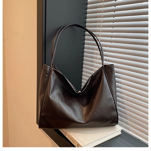 Detailed close-up of brown leather tote bag showing fine texture and long shoulder straps