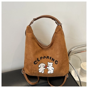 Close-up of brown suede bag with cute white puppy and bear cartoon embroidery