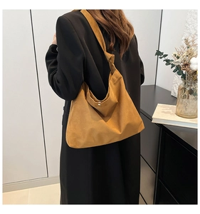 Detail showing high-capacity frosted suede tote bag with knotted shoulder strap and magnetic snap