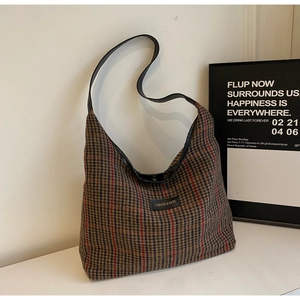 Detailed view of large plaid tote bag with black leather straps and fashion logo patch