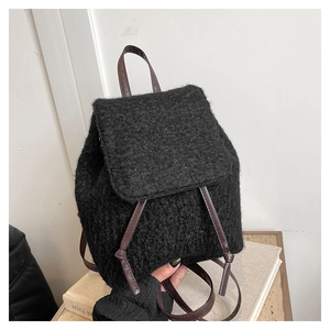 Detail of black wool texture and brown leather straps on an autumn winter backpack