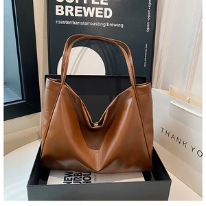 Detail view of large brown vintage tote bag with slim shoulder straps and magnetic closure