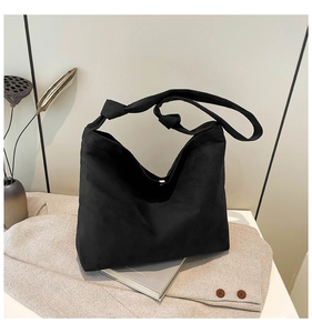 Detail of black matte suede tote bag with stylish knotted strap design on minimalist background