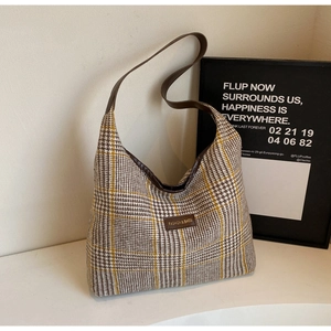 Detailed close-up of houndstooth woven texture and leather logo on large tote bag