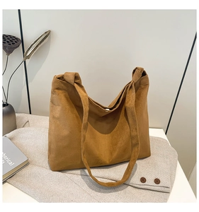 Detail of tan suede tote bag with knotted shoulder strap and magnetic closure detail