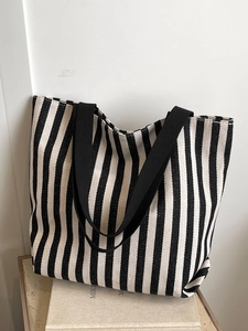 Detailed close-up of a striped canvas tote bag with black woven straps on a clean background