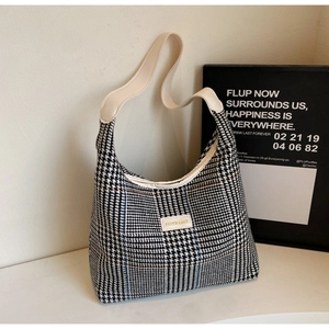 Detailed macro of black and white houndstooth tote bag texture and white leather label