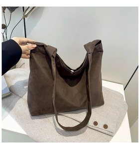 Detail of dark brown faux suede tote bag with magnetic clasp on wool blazer fabric