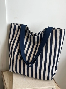 Close-up of blue and white striped canvas tote bag with thick blue handles on books