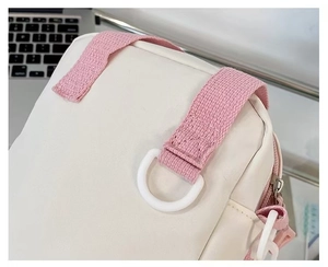 Detail of white canvas bag showing pink woven strap and white D-ring attachment