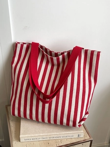 Close-up of red and white striped canvas tote bag with thick red fabric handles on books