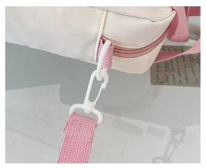 Close-up of the cream crossbody bag showing pink fabric strap and durable plastic hook
