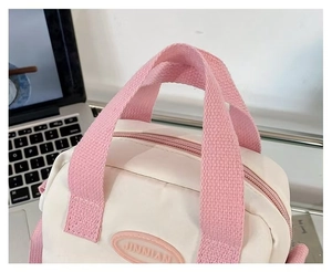 Close-up of a white canvas Ita bag with pink woven straps and JINNIAN logo detail