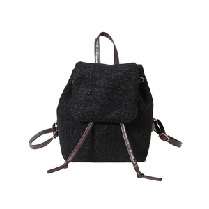 Minimalist black faux shearling drawstring backpack with brown leather accents and gold hardware