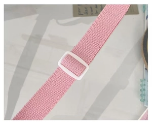 Detail of pink woven nylon shoulder strap with a white plastic adjustable buckle