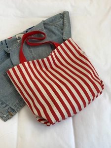 Detail of red and white striped canvas tote bag with durable red woven handles