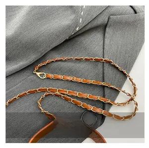 Detailed close-up of brown leather interwoven with golden metal chain and lobster clasps